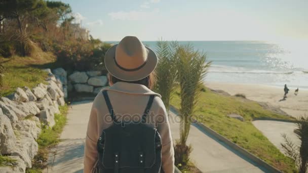 Привлекательная девушка прогуливается вдоль береговой линии в маленьком средиземноморском городке — стоковое видео