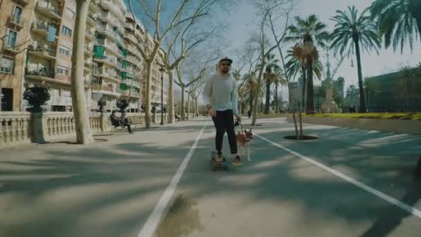 Mann fährt mit seinem Longboard, gefolgt von seinem Hund — Stockvideo