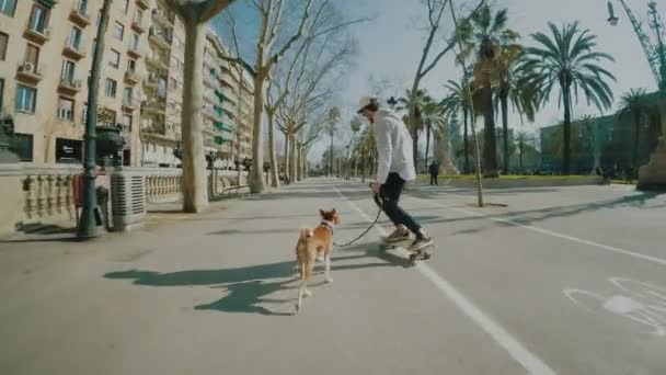 Homem monta seu longboard seguido por seu cão — Vídeo de Stock