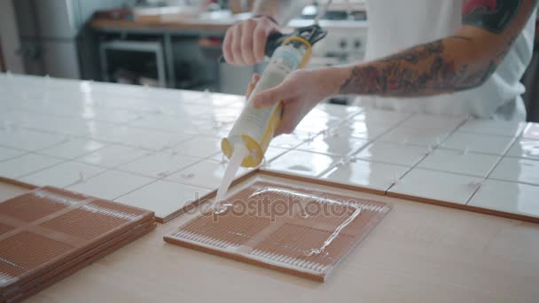 Hombre tatuado aplica baldosas de cerámica en juego de mesa de cocina — Vídeo de stock