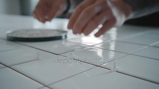 Татуйований чоловік наносить керамічну плитку на кухонний стіл — стокове відео