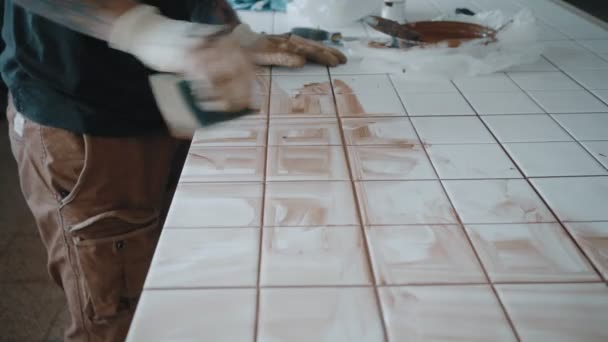 Homem tatuado aplica telhas cerâmicas no conjunto de mesa da cozinha — Vídeo de Stock