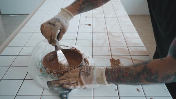 Hombre tatuado aplica baldosas de cerámica en juego de mesa de cocina — Vídeo de stock