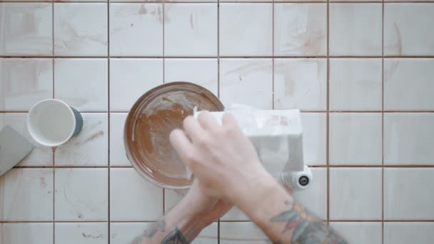 Tattooed man applies ceramic tiles on kitchen table set