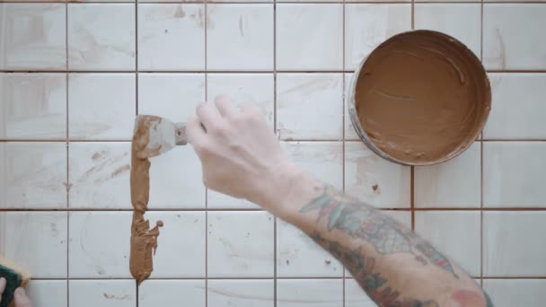 Tattooed man applies ceramic tiles on kitchen table set — Stock Video