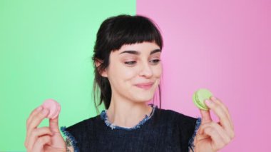 Çekici esmer aydınlık arka izole macarons yiyor