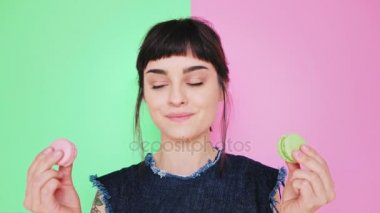 Çekici esmer aydınlık arka izole macarons yiyor