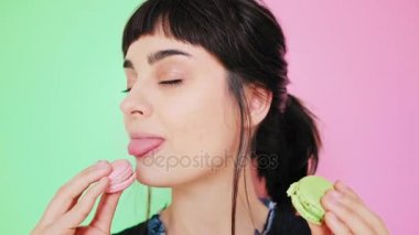 Çekici esmer aydınlık arka izole macarons yiyor
