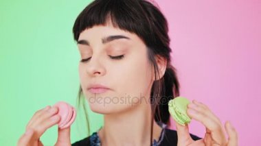 Çekici esmer aydınlık arka izole macarons yiyor