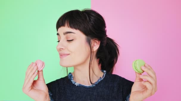Atraktivní brunetka jí macarons izolované na světlé pozadí — Stock video