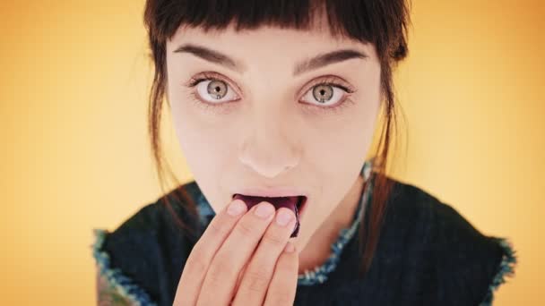 Atrakcyjna brunetka zjada macarons na białym tle na jasnym tle — Wideo stockowe
