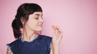 Çekici esmer aydınlık arka izole macarons yiyor