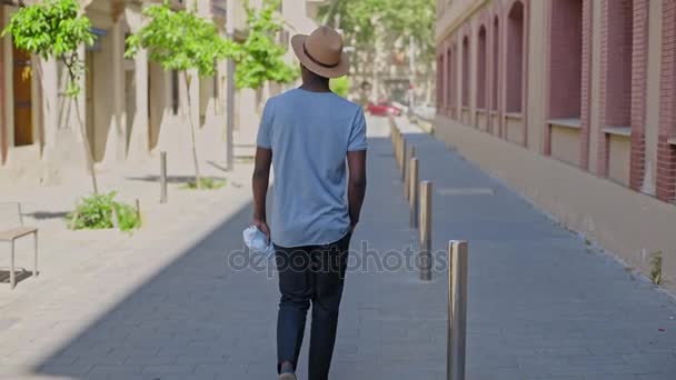 Молодой черный хипстер гуляет по городу. — стоковое видео