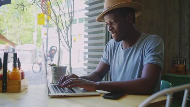 Joven hombre negro se sienta en un café de moda — Vídeos de Stock