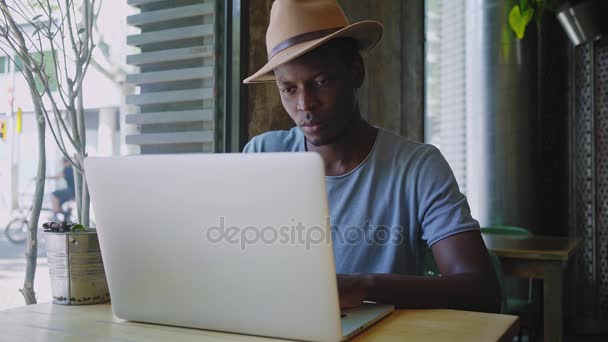 Joven hombre negro se sienta en un café de moda — Vídeo de stock