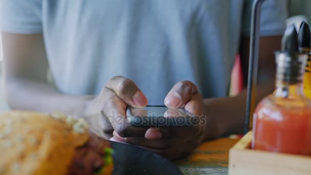 Kafeterya öğle yemeği zamanında tanınmaz halde siyah adam manifatura smartphone cep telefonu ile yukarı kapatın — Stok video