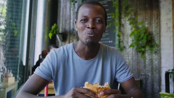 Gelukkig zwarte kerel lachen en Eet smakelijk vlees Hamburger — Stockvideo