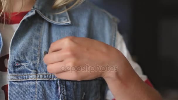 Blond amerikansk flicka sätter en PIN-kod på sin jacka — Stockvideo