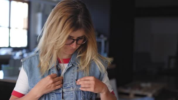 Blonde american girl puts a pin on her jacket — Stock Video