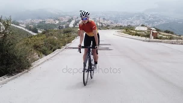 Jovem loira ciclista feminina monta sua bicicleta — Vídeo de Stock