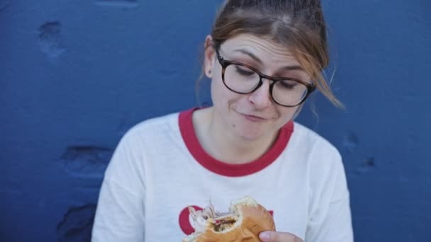 Fiatal nő eszik egy nagy hamburger — Stock videók