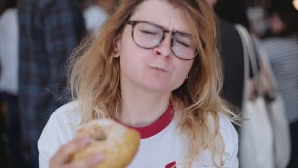 Menina loira morde um delicioso donut — Vídeo de Stock