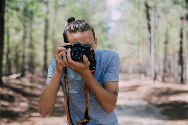 Hipster traveller makes photo in forest — Stock Photo, Image