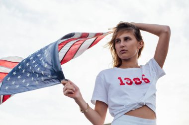 Sarışın kadın model Amerikan bayrağı tutar