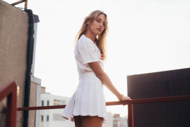 Çatıda beyaz kıyafeti sarışın model