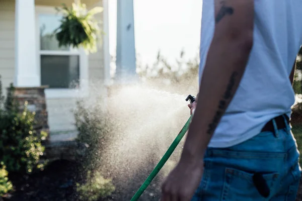 Хіпстер молодий чоловік поливає газон — стокове фото