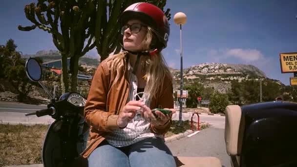 Молода жінка-водій мотоциклів спілкується по телефону — стокове відео