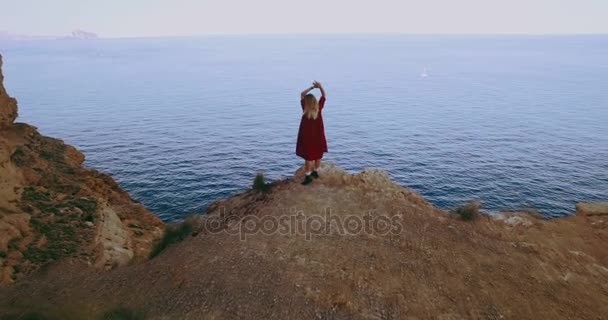 Aerial of young adventure female on cliff on ocean — Stock Video
