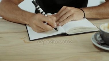 Genç adam kafede oturur ve planı yazıyor