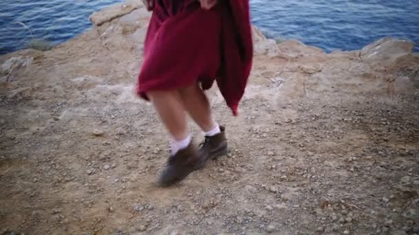 Девушка в красном платье делает кантри платье на скалах — стоковое видео
