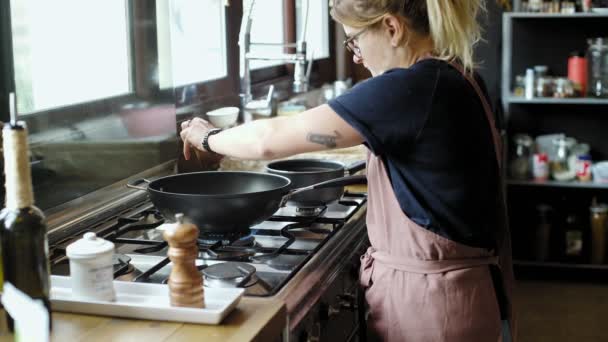 Kvinna i förkläde förbereder middag i wok pan — Stockvideo