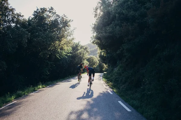 Pyöräilijät ratsastaa tyhjällä tiellä — kuvapankkivalokuva
