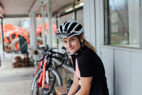 Ung kvinnlig cyklist vilar på bensinstation — Stockfoto