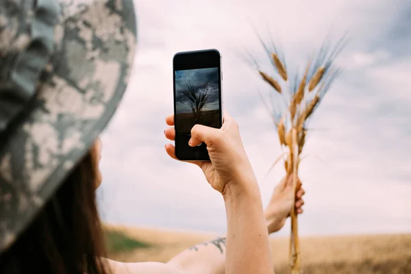 Девушка фотографирует свежесобранную пшеницу — стоковое фото