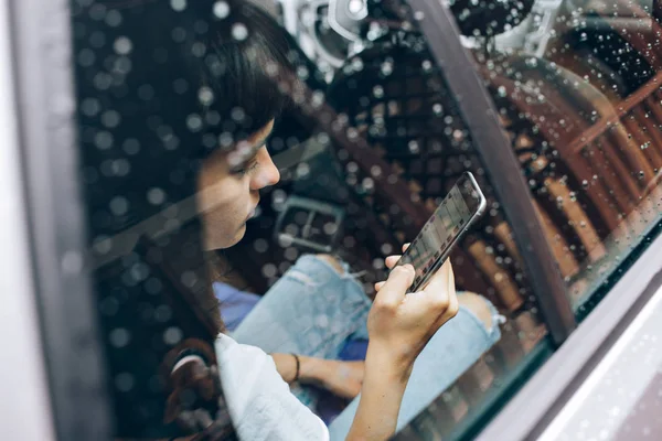 Nainen käyttää älypuhelinta auton sisällä — kuvapankkivalokuva
