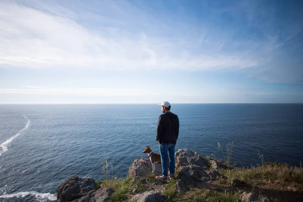 Mies ja koira seisomassa kalliolla — kuvapankkivalokuva