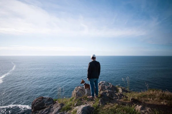 Människan och hunden stående på klippa — Stockfoto