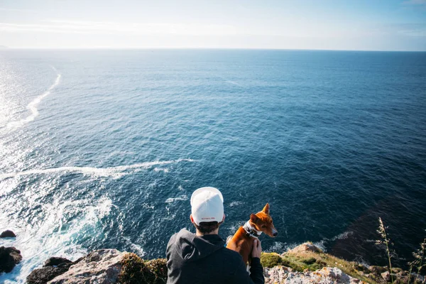 Hombre y perro sentados en el acantilado — Foto de Stock