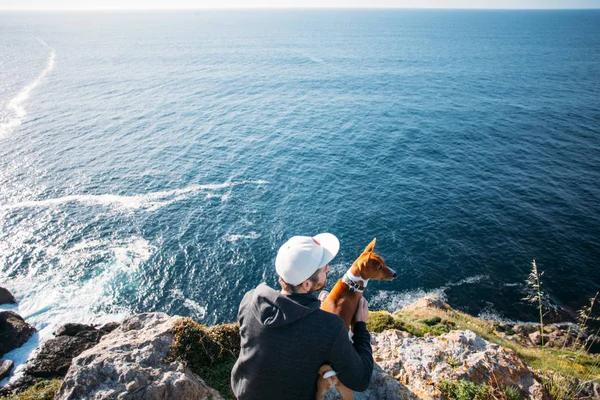 Человек и собака сидят на скале — стоковое фото
