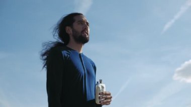 Yorgun bir adam son damla su şişesi içiyor.