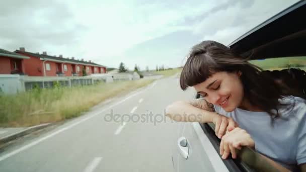 Pretty and young girl hangs out of car window — Stock Video