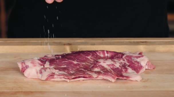 Man marinates and seasons fresh steak with spices — Stock Video