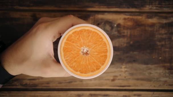 Вид зверху петля рука тримає чашку з апельсином всередині — стокове відео