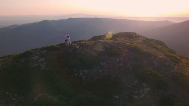 Aerial shot of couple standing on top of mountain — Stock Video