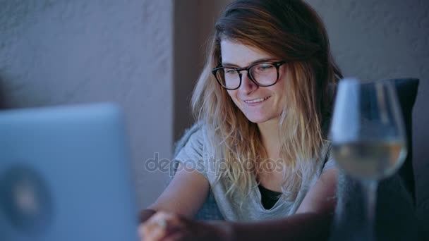 Niedliche blonde Frau mit Brille chatten online auf Laptop — Stockvideo
