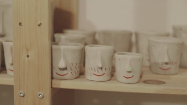 Prateleira de madeira cheia de vasos cerâmicos bonitos brancos — Vídeo de Stock